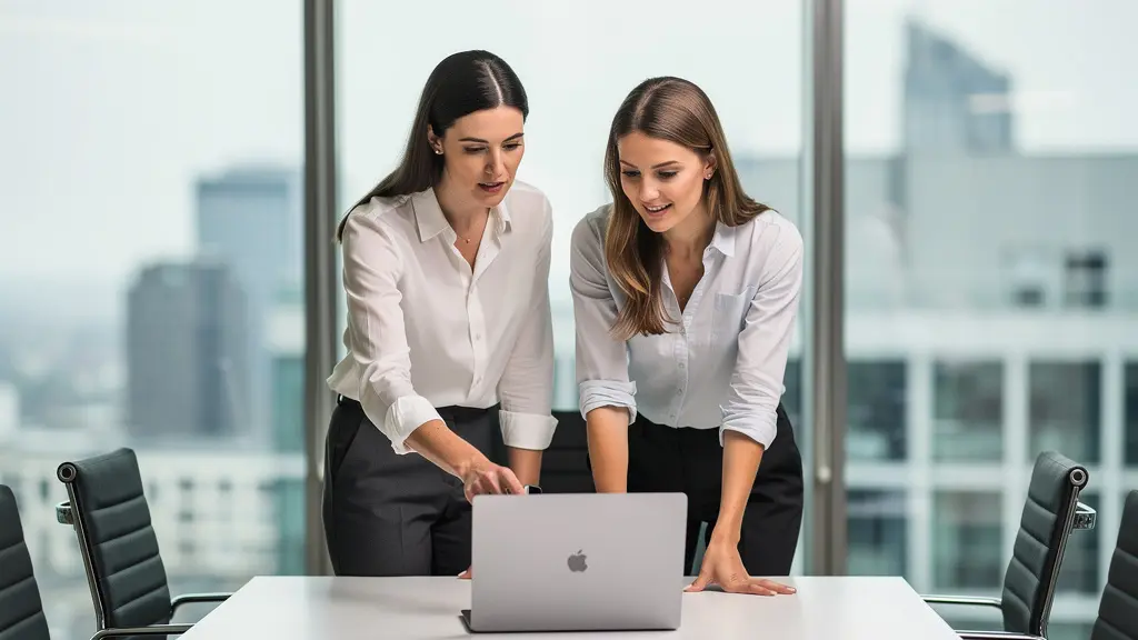 Zwei Kolleginnen besprechen gemeinsam ein Video-Projekt am Laptop im modernen Konferenzraum